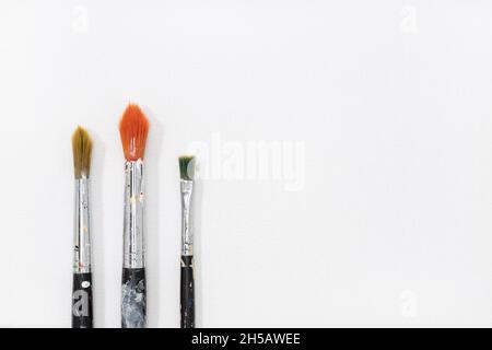 Three paintbrushes on white canvas background. Copy space Stock Photo