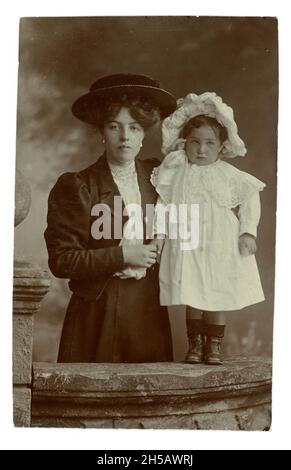 Original Edwardian studio portrait of attractive young mother wearing jacket with puffed sleeves, lace blouse, skirt, & her young child, from the studio of Walter H. Simpson, Kelso, Roxburghshire, Scottish Borders, U.K. circa 1907 Stock Photo