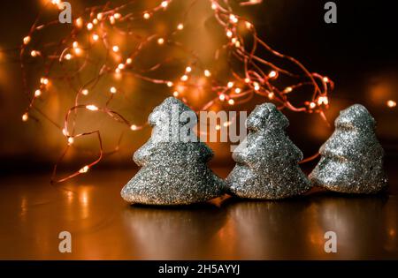 Three christmas toy shining trees on a gold background with lights. Stock Photo