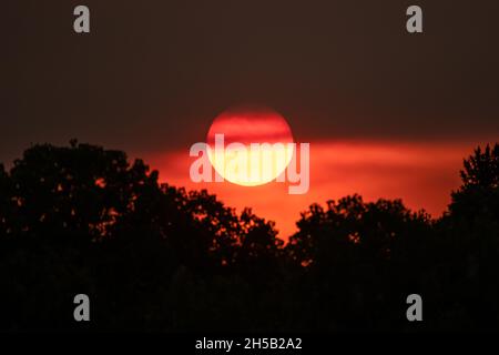 Sun Setting Through Forest Fire Smoke in Colorado sky Stock Photo