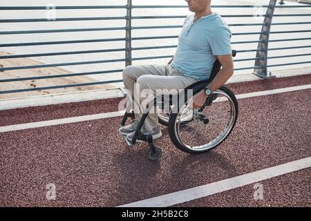 Cropped portrait of man in wheelchair in accessible city environment outdoors, copy space Stock Photo