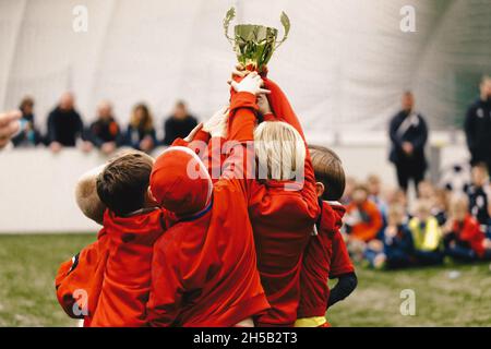 Cheerful Children Celebrating Success in Football Tournament Game. Junior Sports Team Rising Golden Trophy on Confetti Celebration. Soccer Team Celebr Stock Photo