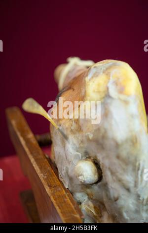 Whole Leg of Parma Ham in Wooden Support, Fibula the horse Bone Used for the Probing of Cured Meats Stock Photo