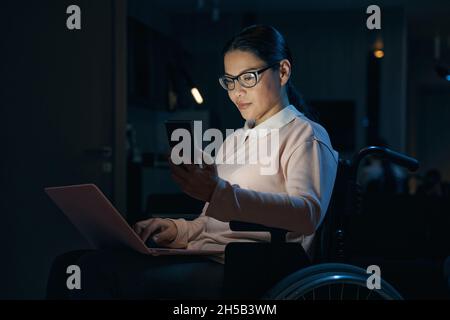 Businesswoman with disability using laptop and smartphone Stock Photo