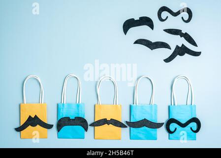 Colorful eco shopping bags and funny fake mustaches on blue Stock Photo