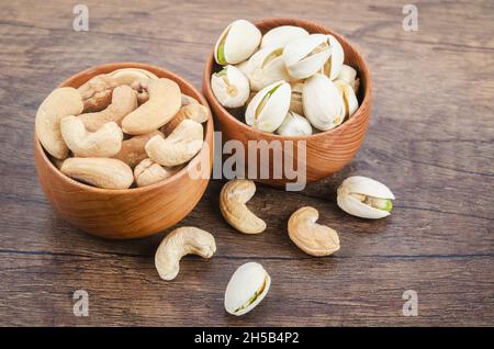 Cashew and pistachio in shell nuts in bowl on wooden table. Stock Photo