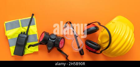 Industrial construction site worker health and safety concept. Work wear protection equipment on orange color background, personal protective gear, to Stock Photo