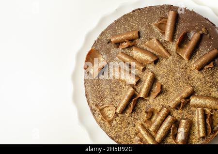 Digestive biscuit base with chocolate cheesecake and pockets of salted caramel sauce, topped with chocolate ganache, milk chocolate curls, and gold sh Stock Photo