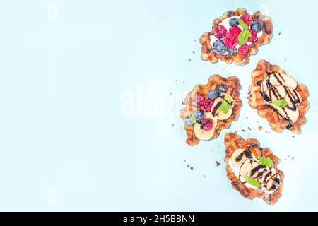 Modern dessert croffle - mixture of croissants and waffles, puff baking waffle iron pan, with berry, fruit cocolate topping Stock Photo