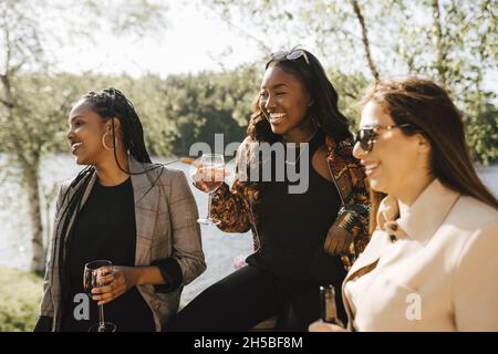 Happy female friends having wine at lakeshore Stock Photo