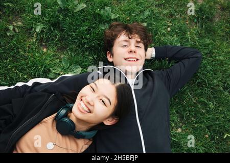 Smiling male and female friends lying on grass Stock Photo