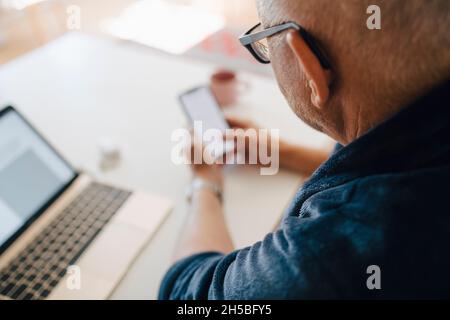 Senior man using smart phone at home Stock Photo
