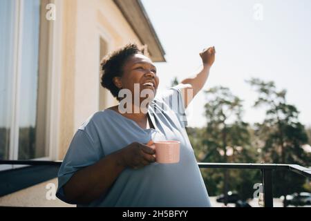 Smiling woman looking away while holding coffee cup in balcony Stock Photo