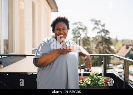 Happy woman having coffee in balcony Stock Photo