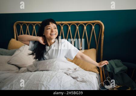 Happy young woman waking up in bed at home Stock Photo