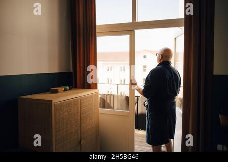 Senior man looking out while standing in doorway Stock Photo