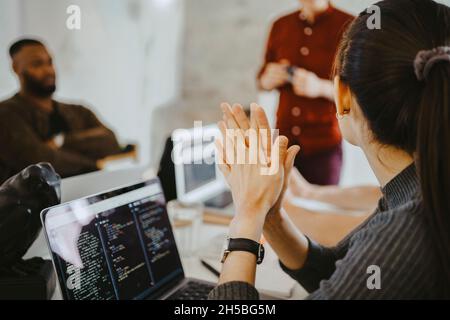 Young female programmer with hands clasped in meeting at office Stock Photo