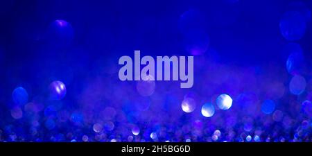 Indigo blue Christmas lights background, banner design. Shiny glowing surface with bokeh, abstract defocused glitter with a sparkles Stock Photo
