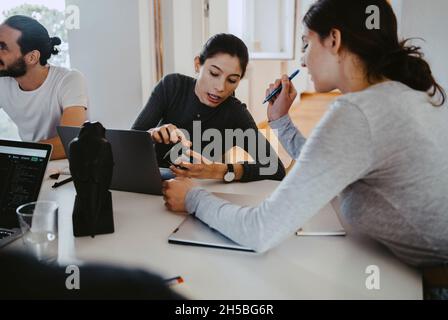 Female professionals discussing over satellite finder at table in creative office Stock Photo