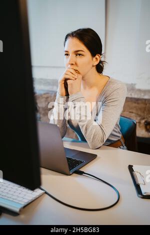 Young female programmer brainstorming over computer in office Stock Photo