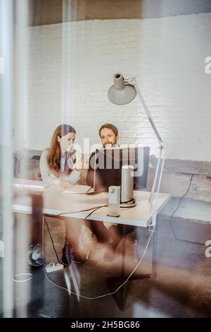 Female and male professionals discussing over computer in office Stock Photo