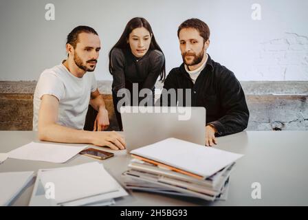 Male and female professionals working over laptop on table in startup company Stock Photo