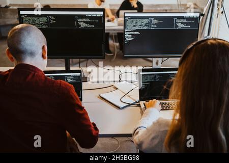 Male and female programmer doing coding over laptop in startup company Stock Photo