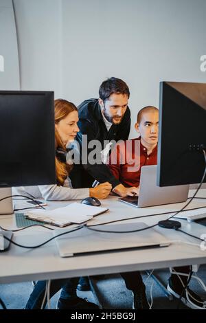 Male programmer doing coding with colleagues in startup company Stock Photo