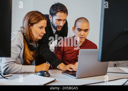Female and male programmers concentrating while coding over laptop at office Stock Photo