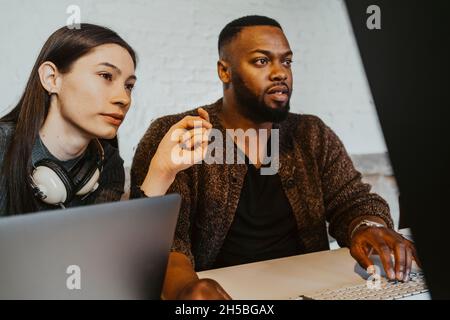 Male and female hackers working on computer at startup company Stock Photo