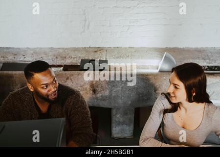 Female and male programmers talking while working on computer in creative office Stock Photo