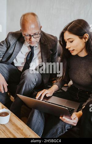Young female programmer discussing over laptop with male advisor at office Stock Photo