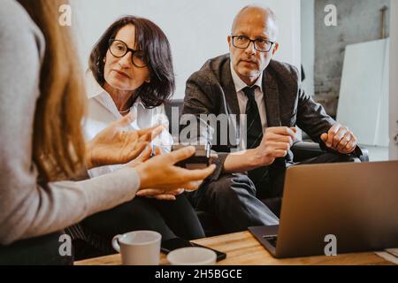 Senior female mentor discussing over satellite finder with programmer at office Stock Photo