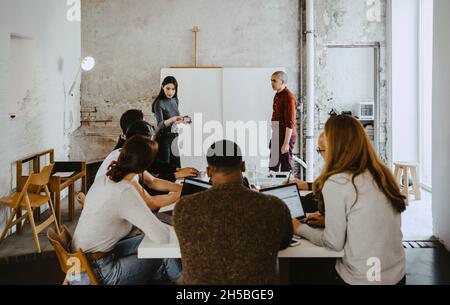 Female hacker presenting in front of colleagues at startup company Stock Photo