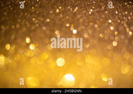 Golden glittering background. Christmas sparkles, texture with bokeh and shiny lights photo Stock Photo