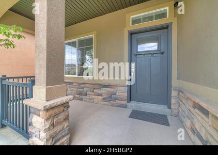 Front porch with security camera above the gray front door with window panel and lockbox Stock Photo