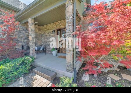 Entrance of a house with plants and small red trees outside Stock Photo