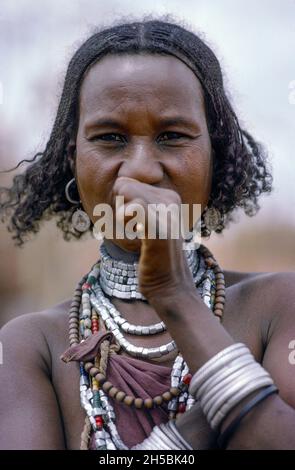 Africa, Kenya, Moyale 1976. Borana women on the Ethiopian - Kenya border. She is wearing aluminium or alloy bracelets and necklaces and chewing a stick to clean her teeth. Stock Photo