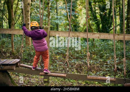 adventure climbing high wire park - people on course in mountain helmet and safety equipment. Stock Photo