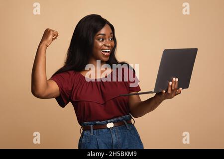 Emotional young black woman enjoying her new modern laptop Stock Photo