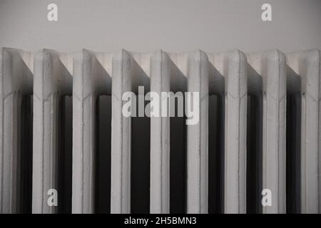 Close up of white old style radiator, with a white wall behind. Stock Photo