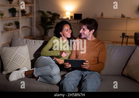 Cheerful Young Spouses Using Digital Tablet Together At Home Stock Photo