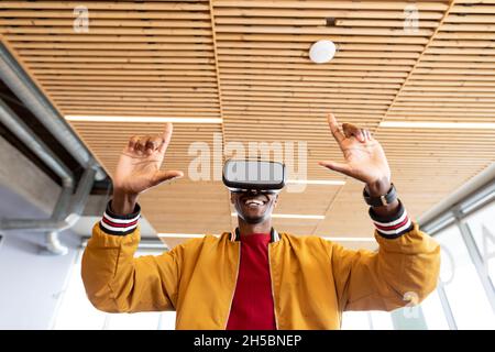 Smiling businessman in casuals using virtual reality headset in creative office Stock Photo