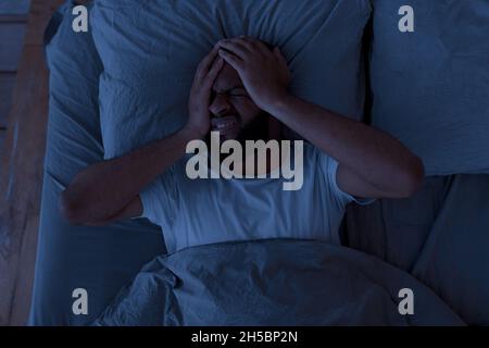 Black man suffering from headache or migraine at night Stock Photo