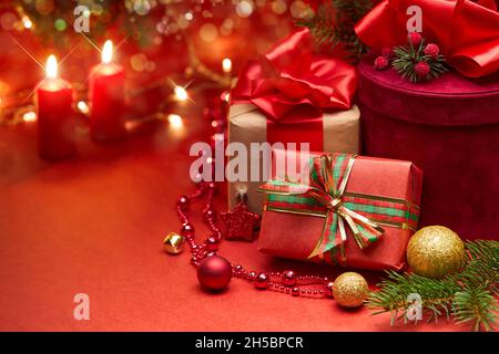 Christmas gift boxes and candles on a red background. Stock Photo