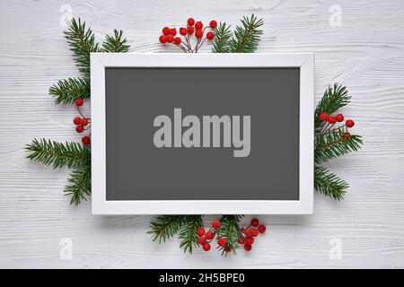 Christmas composition template. Frame, spruce twigs and Christmas tree decorations on a light wooden background. Top view. Stock Photo