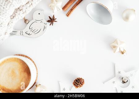 Vintage Christmas composition. Christmas frame made of o decorations, coffee cup, bell, knitted scarf, beige bauble on white table. Rustic style. Flat Stock Photo