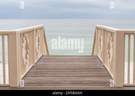 High angle view of wooden pavilion boardwalk railing stairs steps leading to beach at Gulf of Mexico at Seaside, Florida on cloudy day Stock Photo