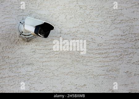 Surveillance camera on a wall pointing down Stock Photo