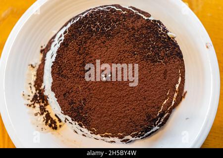 Macro closeup flat top above view of chocolate cocoa powder chips vanilla mascarpone traditional Italian tiramisu dessert with egg yolks gelato base o Stock Photo